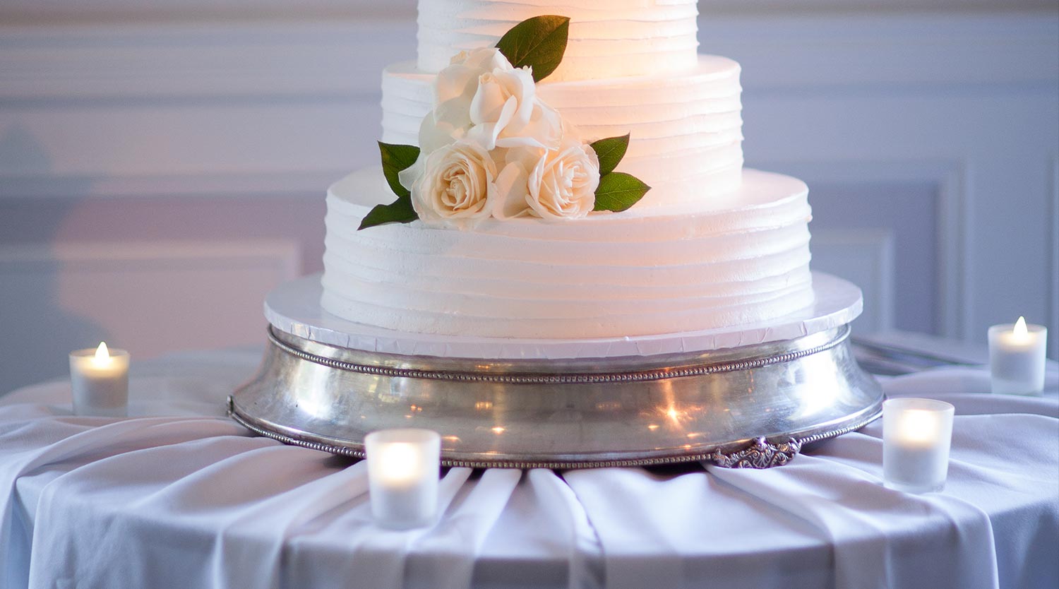 Photo: close up clean white wedding cake with white flowers