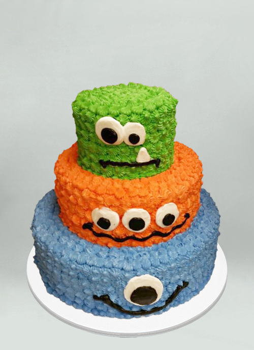 Photo: 3 tire frosted green, orange, blue cake with monster face on each tier