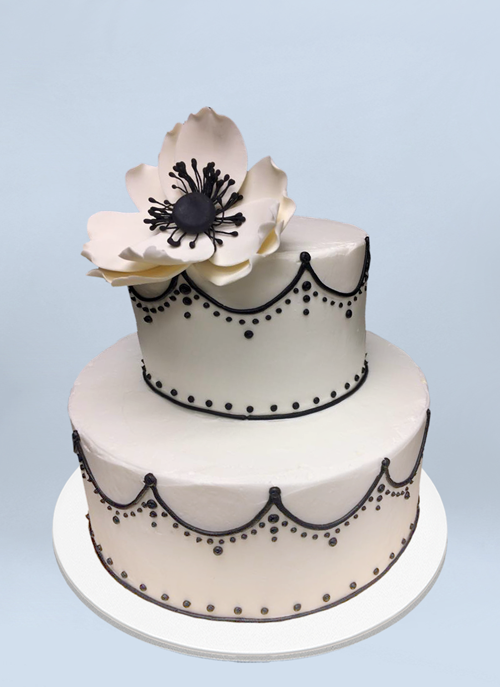 Photo: white frosted 2 tier cake with black piping and large white sugar flower