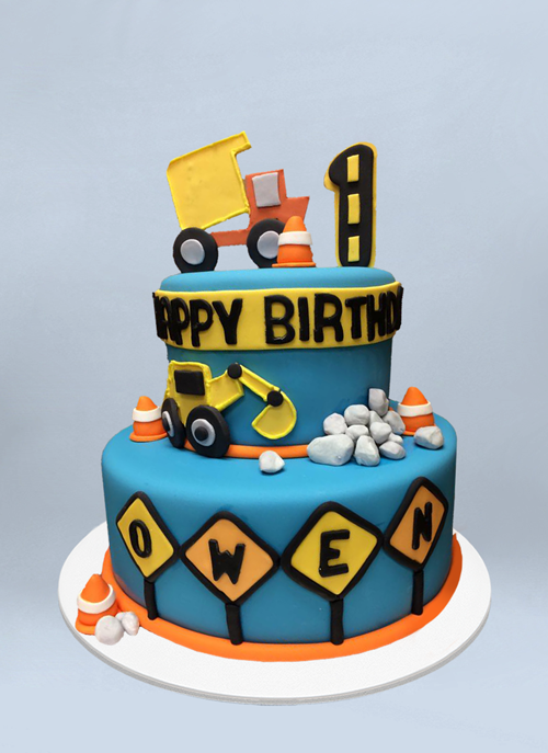Photo: fondant cake with fondant construction cones, rocks, trucks and signs around the tiers