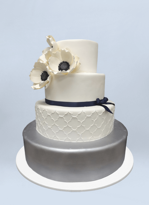 Photo: silver tier, clean white pattern, blue ribbon and white flower on top