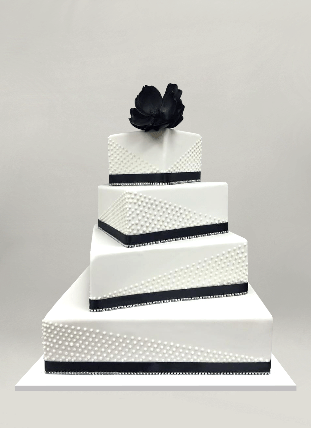 Photo: four rotated square tiers with black ribbon, beaded dot piping and black sugar flower